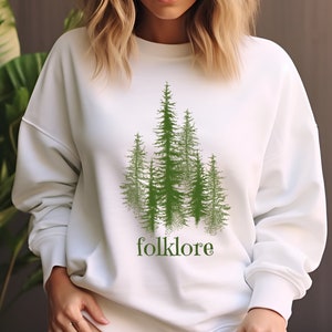 May include: White sweatshirt with a green graphic of a forest with the word "folklore" printed below.