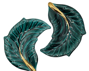 May include: Two green ceramic leaf-shaped dishes with gold accents. The dishes are perfect for serving snacks or appetizers.