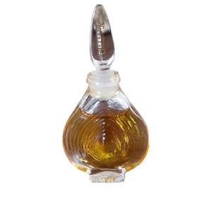 May include: A clear glass bottle with a textured surface and a silver cap. The bottle is filled with a golden liquid. The cap has the word "Givenchy" engraved on it.