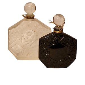 Peut inclure: Deux flacons de parfum octogonaux en verre avec des motifs ornés. Un flacon est transparent et l'autre est noir.