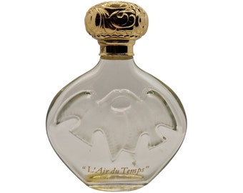 May include: A clear glass bottle of perfume with a gold cap and a gold inscription that reads "L'Air du Temps" Eau de Toilette.