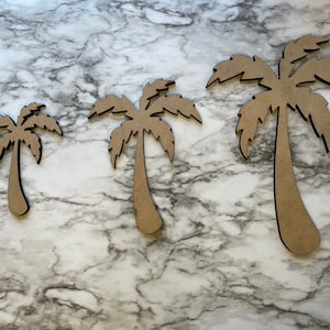 Peut inclure: Trois découpes de palmiers en bois de différentes tailles. Les arbres sont de couleur marron clair avec des contours noirs et sont disposés du plus petit au plus grand. Le fond est un motif marbré.