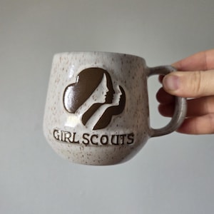 May include: A set of three ceramic mugs with a speckled, matte finish. The mugs are in shades of cream, light gray, and dark gray. Each mug has a simple, minimalist design, perfect for coffee or tea.