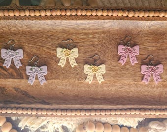 Rose Bows made with polymer clay. Lightweight, hypoallergenic, choose from pink, yellow, or lavender.
