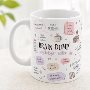 Può includere: Una tazza in ceramica bianca con illustrazioni disegnate a mano e testi che includono "BRAIN DUMP psychologist edition," "I need more coffee," "good boundaries," "reflect & reset," "so many appointments," e "SUPERVISION BOOKED."