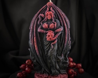 May include: A sculpted candle depicting Lilith, a figure from mythology. The candle is primarily black and red, featuring a woman holding a skull, with snakes and wings. The base of the candle reads "LILITH".