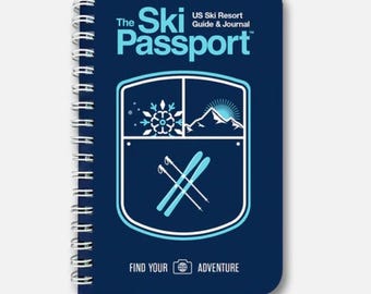 May include: A navy blue spiral-bound notebook titled "The Ski Passport" with white text and a graphic of skis, mountains, and a snowflake. The notebook also includes the text "US Ski Resort Guide & Journal" and "Find Your Adventure."