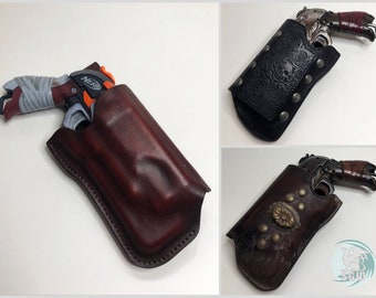 May include: Three different leather holsters for toy guns. The holsters are brown, black, and distressed brown. The guns are a Nerf gun, a silver toy gun, and a brown toy gun.