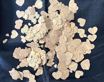 May include: A pile of paper heart confetti made from old book pages. The hearts are scattered on a dark blue fabric background.