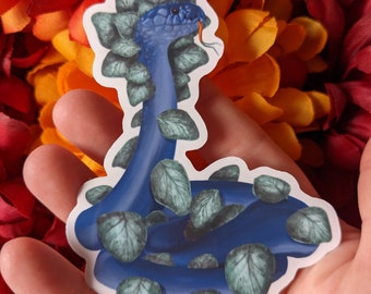 Può includere: Un adesivo di un serpente blu con foglie verdi. Il serpente è arrotolato con la testa alzata e la bocca aperta. L'adesivo è su uno sfondo bianco.