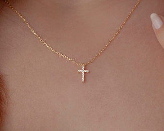 May include: A gold chain necklace with a small, sparkling cross pendant.
