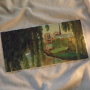 May include: A painting of a church with a tall spire, surrounded by trees and a river. The church is painted in a light brown color, and the trees are a dark green. The river is a light blue color.