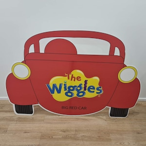 K&ouml;nnte beinhalten: Ein roter Papp-Ausschnitt eines Autos mit den Worten "The Wiggles" und "Big Red Car" darauf.