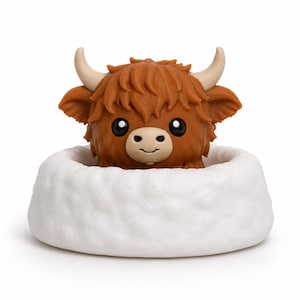 May include: A brown Highland cow figurine with shaggy hair, curved horns, and large black eyes, emerging from a textured white circular base. The cow has a light tan muzzle and a small smile, presented as a singular decorative object.