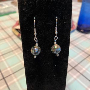 May include: A pair of silver dangle earrings with iridescent black and green round beads.