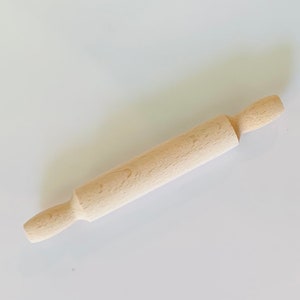 May include: A wooden rolling pin with rounded ends. The rolling pin is made of light brown wood and is about 12 inches long.