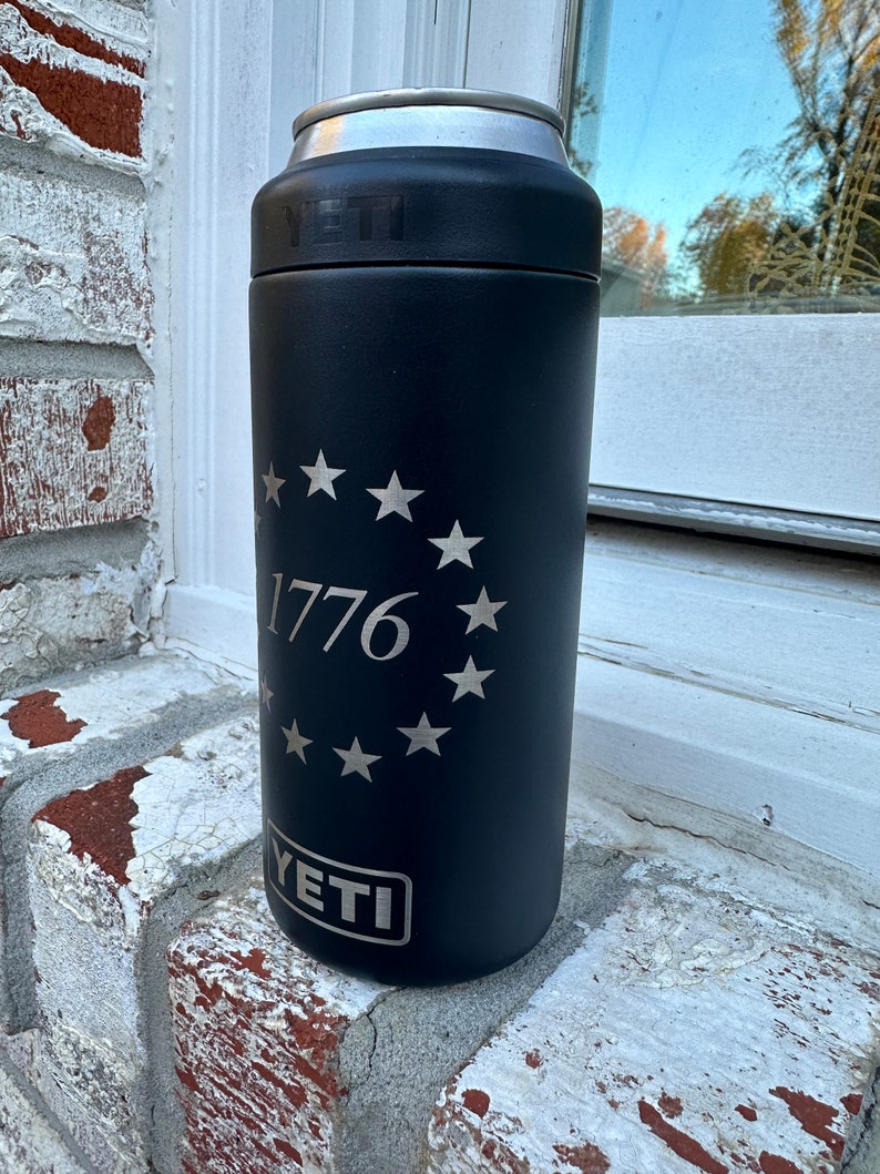 May include: Black YETI Rambler 12 oz. can insulator with a silver 1776 and a circle of stars around it.