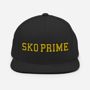Puede incluir: Gorra de béisbol negra ajustada con un logotipo bordado en oro que dice "SKO PRIME".