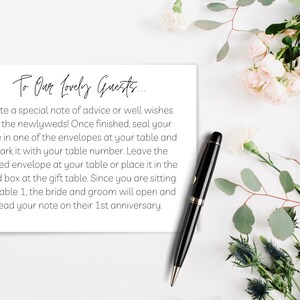 Può includere: Un biglietto bianco con la scritta "To Our Lovely Guests..." in elegante calligrafia, con istruzioni per gli invitati al matrimonio. Una penna nera e una composizione floreale sono anch'esse presenti.