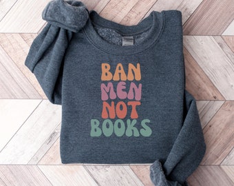 May include: A dark grey sweatshirt with the text "BAN MEN NOT BOOKS" in colourful, retro-style lettering.