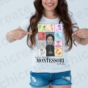 May include: A white t-shirt with a colorful graphic of a girl in a classroom setting. The graphic includes the text "in my MONTESSORI era".
