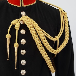 May include: A black military uniform jacket with gold braid trim and buttons. The jacket has a red collar and gold braid shoulder straps.