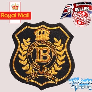 Puede incluir: Parche bordado en negro y dorado con una corona, las letras "PARIS BALMAIN PARIS" y la letra "B" en el centro. El parche tiene el texto "EST. 1945" en la parte inferior.