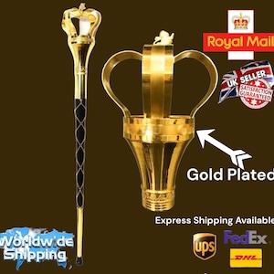 May include: A gold-plated walking stick with a crown-shaped top. The stick has a black leather grip and a gold-plated base. The crown is adorned with a small figure on top. The text "Gold Plated" is visible in the image.
