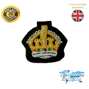 May include: A gold embroidered crown patch with red, blue, and green jewels. The crown is on a black felt backing.