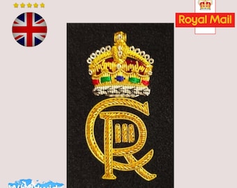 May include: Gold embroidered patch with a crown and the letters "C.R." on a black background. The crown is red, gold, green, and blue. The patch is for sewing or ironing onto fabric.