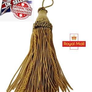 May include: A gold tassel with a loop at the top. The tassel is made of a braided cord and has a fringe at the bottom.