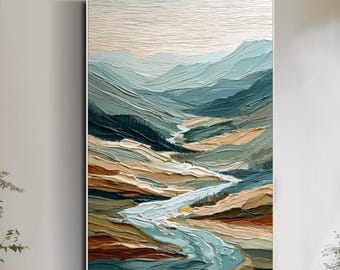 May include: An abstract landscape painting featuring a river winding through layered mountains. The artwork uses a palette of blues, greens, and browns, with textured brushstrokes creating depth. The painting is displayed in a white frame, adding a modern touch to the artwork.