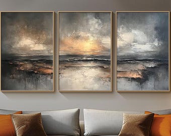 May include: Three abstract landscape paintings in gold, gray, and white tones. The paintings are framed in a thin, gold frame and are hung on a gray wall. The paintings depict a seascape with a sunset in the background.