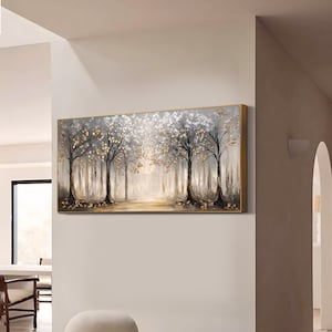 May include: A rectangular wall art painting featuring a forest scene with dark tree trunks, white foliage, and metallic gold leaf accents. The artwork is set within a thin gold frame and depicts a light-filled path between the trees.