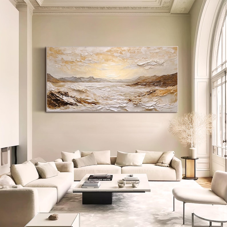 May include: A large rectangular landscape painting featuring a textured impasto technique in shades of cream, white, and metallic gold. The artwork depicts a serene coastal scene with rolling hills, rocky shorelines, and a bright, glowing horizon.