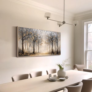 May include: A rectangular wall art canvas featuring a forest landscape with dark tree trunks, grey foliage, and metallic gold leaf accents. The painting depicts a path leading into a bright, light-filled center, framed by a thin, light-colored wooden border.