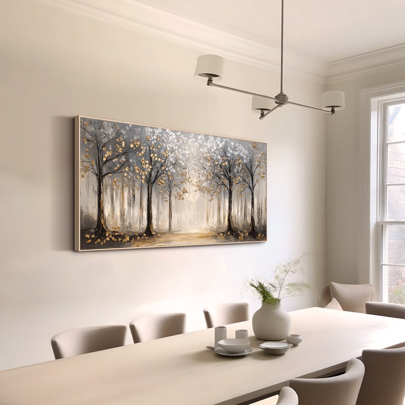 May include: A rectangular wall art canvas featuring a forest landscape with dark tree trunks, grey foliage, and metallic gold leaf accents. The painting depicts a path leading into a bright, light-filled center, framed by a thin, light-colored wooden border.