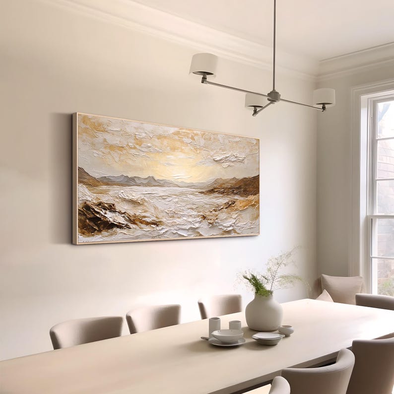 May include: A large rectangular landscape painting featuring a textured impasto technique in shades of white, cream, gold, and brown. The artwork depicts a serene coastal scene with rolling hills, a calm body of water, and a bright, glowing sky.