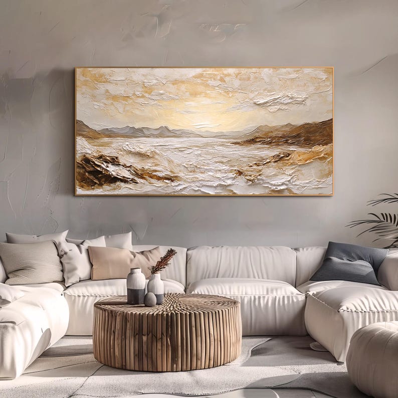 May include: A rectangular landscape painting featuring a textured impasto technique in shades of cream, white, and golden brown. The artwork depicts a coastal scene with rolling waves, rocky shorelines, and distant mountains under a bright sky.