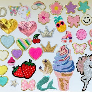 May include: A collection of colourful iron-on patches featuring various designs, including hearts, stars, unicorns, flowers, crowns, butterflies, and a pineapple. The patches are perfect for adding a personal touch to clothing, bags, or other accessories.