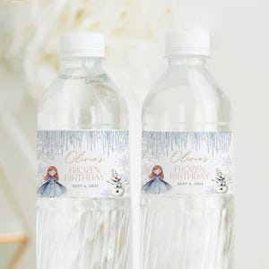 Pu&ograve; includere: Due bottiglie d'acqua in plastica trasparente con etichette blu e bianche raffiguranti una bambina dei cartoni animati e un pupazzo di neve. Le etichette riportano la scritta "Olivia's Frozen Birthday Sept 4, 2024".