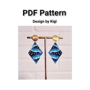 May include: A pair of blue and black beaded earrings with a geometric diamond shape, hanging from gold earring hooks. The earrings are displayed on a gold stand against a white brick wall. The text "PDF Pattern Design by Kigi" is displayed above the earrings.