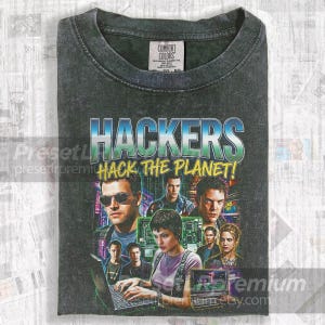 Puede incluir: Camiseta Comfort Colors gris oscuro con un gráfico que dice "HACKERS" en azul y verde, y la frase "HACK THE PLANET!" en amarillo. El gráfico incluye imágenes de personas y componentes informáticos.