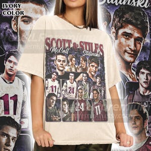 Può includere: Una t-shirt a maniche corte color avorio con una stampa grafica di Scott McCall e Stiles Stilinski. Il design include diversi ritratti e foto d'azione dei personaggi con maglie numerate 11 e 24, con il testo "SCOTT & STILES" e "McCall" e "Stilinski" stampato sopra.