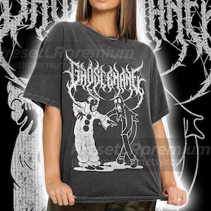 May include: Dark gray t-shirt featuring a white graphic of a clown and a ghost with the text "GROSSEMANIE" in a gothic font. The shirt has a vintage, worn look.