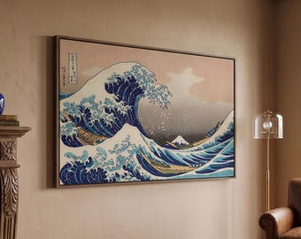 May include: A framed rectangular wall art print featuring a stylised depiction of a large blue ocean wave with white foam crests, dark blue water, and a distant mountain peak, displayed in a room with a fireplace, leather chair, and rug.