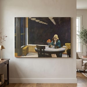 May include: A rectangular wall art print depicting a person wearing a yellow hat and a teal coat sitting at a round table in a dark interior. The scene includes a bowl of fruit on the table, a radiator, and a dark window frame against a wall.