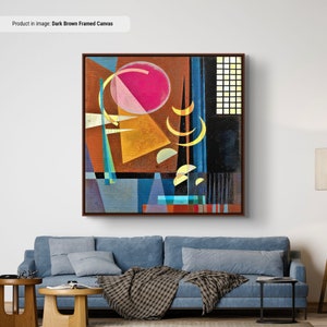 Puede incluir: Impresión de arte abstracto con formas geométricas en tonos de amarillo, azul, rosa y marrón. La impresión está enmarcada en madera marrón oscura.