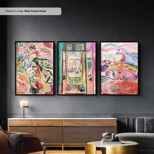 May include: Three black framed posters with colorful abstract paintings. The left poster features a woman in a pink and green dress walking on a beach. The middle poster shows a window with a view of a harbor with boats. The right poster shows a pink building with a red roof and a blue sky.