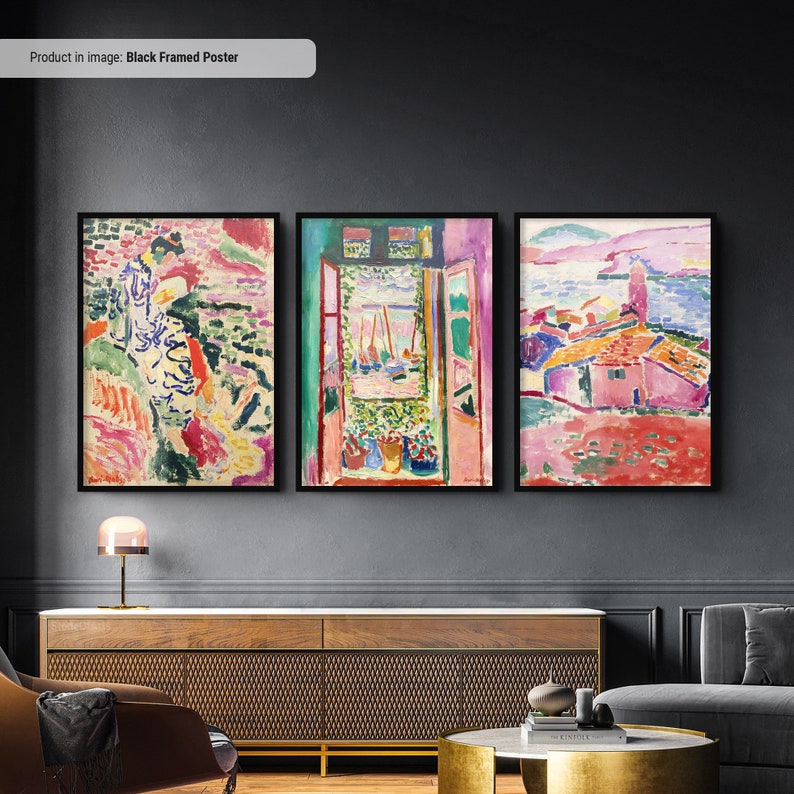 May include: Three black framed posters with colorful abstract paintings. The left poster features a woman in a pink and green dress walking on a beach. The middle poster shows a window with a view of a harbor with boats. The right poster shows a pink building with a red roof and a blue sky.